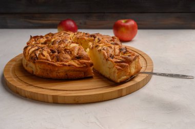 Beyaz arka planda kürek kemiğinde kesik bir parça olan Cornish elmalı turtası. İki elmanın yanında. Metnin için boşluk kopyala