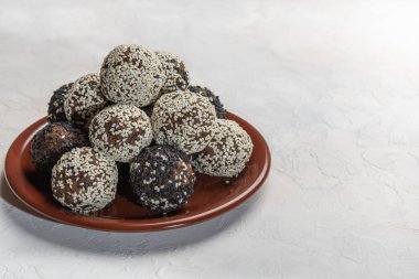 Beyaz arka planda kahverengi seramik tabakta ev yapımı enerji topları.