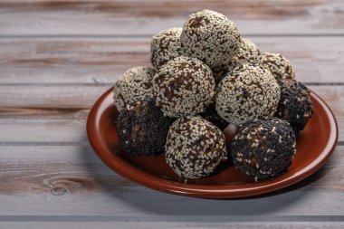 Ahşap bir zeminde kahverengi bir tabakta ev yapımı enerji topları.