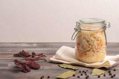 Ev yapımı lahana konservesi kavanozda peçeteye konmuş ve ahşap bir masanın üzerinde sonbahar yaprakları var. Kırsal biçim