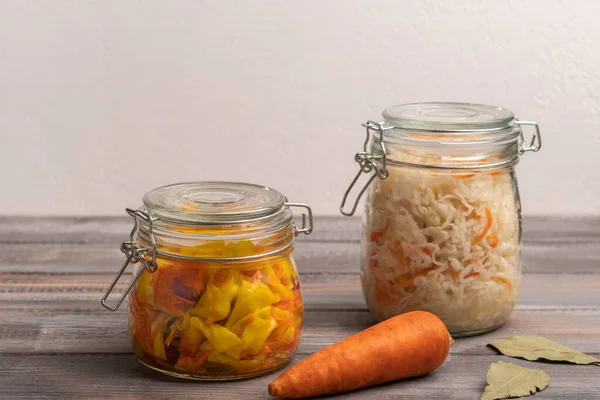 Chou en conserve fait maison avec des carottes dans des pots avec des feuilles de laurier sur une table en bois. Style rustique — Photo