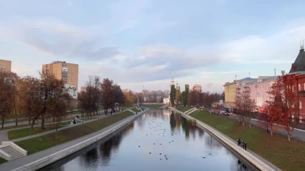 Panoramic sunset view of the river, promenade, old churches. People from the shore feed the ducks — ストック動画