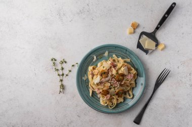Mantarlı makarna, pastırma ve beyaz tabakta parmesan peyniri. Çatallı, ahşap arka plan manzaralı.