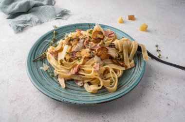 Mantarlı makarna, pastırma, beyaz tabakta parmesan peyniri çatal ve peçeteyle yakın plan.
