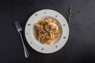 Mantarlı makarna, pastırma ve beyaz tabakta parmesan peyniri. Koyu grafit ahşap arka plan manzaralı.