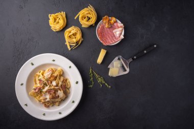 Mantarlı makarna, pastırma ve parmesan peyniri koyu grafit ahşap arka plan manzaralı.