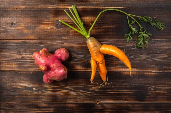 Trendig ful ekologisk morot med toppar och potatis från hemmet trädgård på en trä bakgrund — Stockfoto