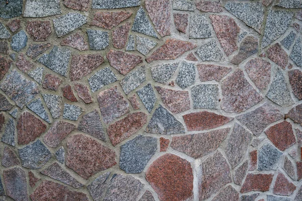 Achtergrond muur van rood en grijs graniet stukken stenen bevestigd met cement — Stockfoto