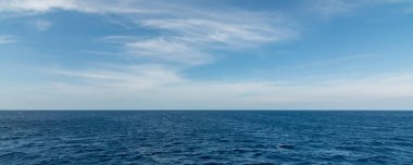 Panorama arka planında küçük dalgalar, köpükler ve bulutlu gökyüzü.