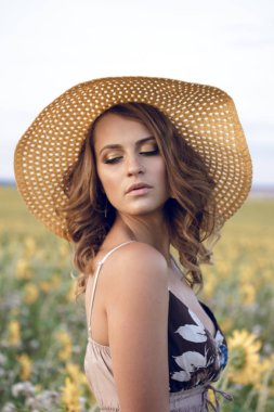 Ayçiçeği tarlasında bir şapka giyen genç güzel kadın