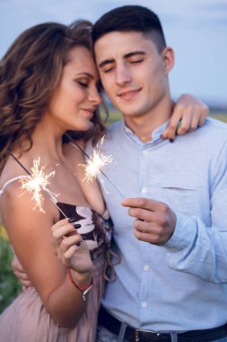 Mutlu bir çift bengal ışıklar ayçiçeği arka plan üzerinde tutun. akşam gece tatil