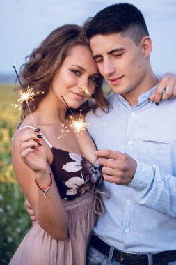 Mutlu bir çift bengal ışıklar ayçiçeği arka plan üzerinde tutun. akşam gece tatil