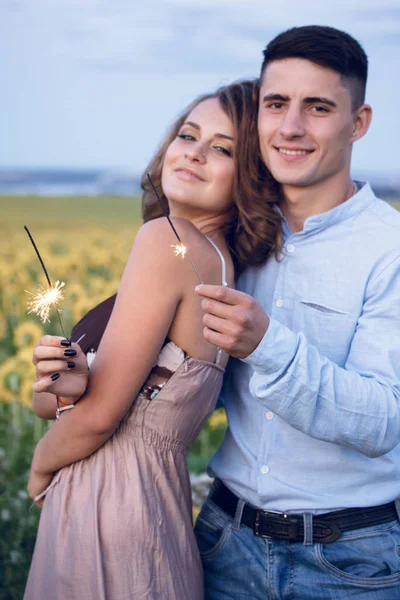 Mutlu bir çift bengal ışıklar ayçiçeği arka plan üzerinde tutun. akşam gece tatil