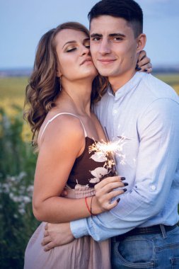 Mutlu bir çift bengal ışıklar ayçiçeği arka plan üzerinde tutun. akşam gece tatil