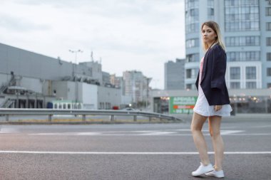 Şehirde uzun beyaz gömlek ve ceket giyen sokak yürüyüş çıplak ayaklı güzel kadın