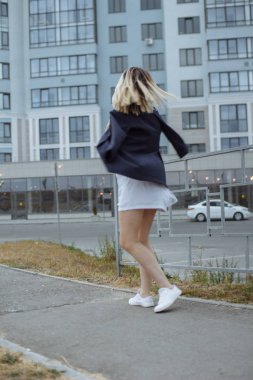 Şehirde uzun beyaz gömlek ve ceket giyen sokak yürüyüş çıplak ayaklı güzel kadın