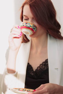 Güzel redhear kadın beyaz ceket, yüksek topuklu ve siyah gömlek balcone oturan