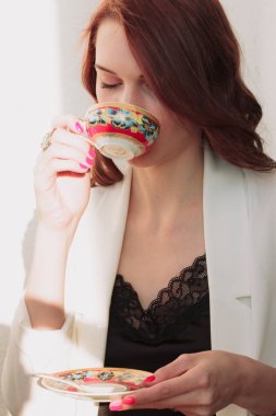 Güzel redhear kadın beyaz ceket, yüksek topuklu ve siyah gömlek balcone oturan