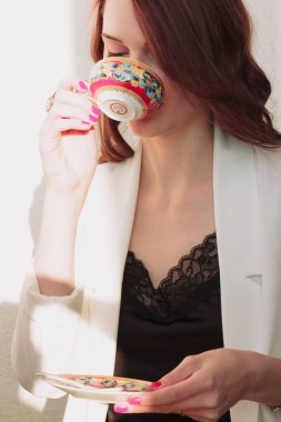 Güzel redhear kadın beyaz ceket, yüksek topuklu ve siyah gömlek balcone oturan