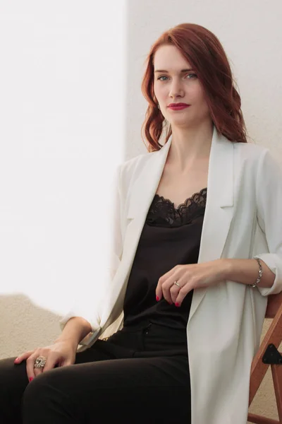 Mooie Redhear Vrouw Witte Jas Hoge Hakken Zwarte Shirt Zitten — Stockfoto