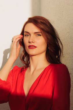 Kırmızı bir elbise ve güneş gözlüğü gün batımında balkonda genç kız esmer ayakta