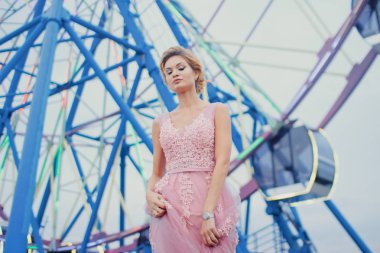 Uzun pembe gece elbisesi yolu Park'ta yürüyordunuz genç güzel kadın. Moda stil açık havada dönme dolap yakınındaki güzel güzel kız portresi