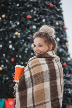 kış tatili, sıcak içecekler, yünlü ekose ve insanlar - genç kadınla mutlu Noel ışıkları açık havada kahve