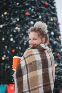 kış tatili, sıcak içecekler, yünlü ekose ve insanlar - genç kadınla mutlu Noel ışıkları açık havada kahve