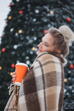 kış tatili, sıcak içecekler, yünlü ekose ve insanlar - genç kadınla mutlu Noel ışıkları açık havada kahve