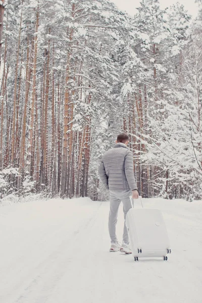 Портрет Молодого Модного Человека Белой Одежде Гуляющего Снегу Чемоданом Идущего — стоковое фото