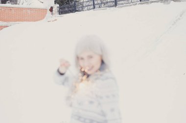 Mutlu ve gülümseyen kız sokakta kar yağışı sırasında Bengal ışık tutar. Kış konsepti. Yeni yıl kavramı.