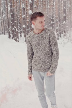 Dışarıda kışın poz bir gri kapşonlu yakışıklı bir adam. Renkli duman bir arka plan üzerinde duran genç adam