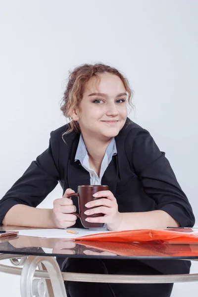Education, people, children and school concept - Portrait of young beautiful woman sitting at desk enjoying cup of coffee while working or studying at small home office or in the student dorm. Indoors — Stock Photo, Image
