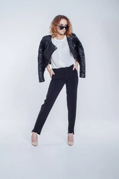 Mujer sensual de moda bastante joven posando sobre fondo blanco con un traje de chaqueta de cuero estilo hipster. Elegante chica de moda hipster en ropa negra y camisa blanca . —  Fotos de Stock