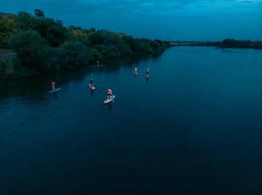 Göldeki SUP tahtalı turistlerin en iyi görüntüsü. Sörf yapan insanlarla dolu güzel, berrak bir su. Arka planda kürek çeken insanların olduğu deniz manzarası