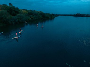 Göldeki SUP tahtalı turistlerin en iyi görüntüsü. Sörf yapan insanlarla dolu güzel, berrak bir su. Arka planda kürek çeken insanların olduğu deniz manzarası