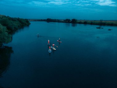 Göldeki SUP tahtalı turistlerin en iyi görüntüsü. Sörf yapan insanlarla dolu güzel, berrak bir su. Arka planda kürek çeken insanların olduğu deniz manzarası