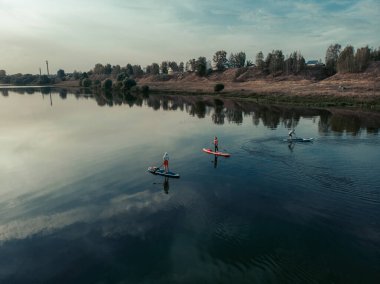 Göldeki SUP tahtalı turistlerin en iyi görüntüsü. Sörf yapan insanlarla dolu güzel, berrak bir su. Arka planda kürek çeken insanların olduğu deniz manzarası