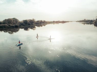 Göldeki SUP tahtalı turistlerin en iyi görüntüsü. Sörf yapan insanlarla dolu güzel, berrak bir su. Arka planda kürek çeken insanların olduğu deniz manzarası