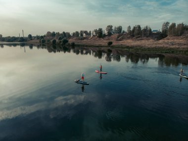 Göldeki SUP tahtalı turistlerin en iyi görüntüsü. Sörf yapan insanlarla dolu güzel, berrak bir su. Arka planda kürek çeken insanların olduğu deniz manzarası