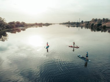 Göldeki SUP tahtalı turistlerin en iyi görüntüsü. Sörf yapan insanlarla dolu güzel, berrak bir su. Arka planda kürek çeken insanların olduğu deniz manzarası