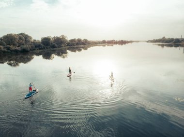 Göldeki SUP tahtalı turistlerin en iyi görüntüsü. Sörf yapan insanlarla dolu güzel, berrak bir su. Arka planda kürek çeken insanların olduğu deniz manzarası