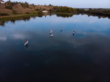 Göldeki SUP tahtalı turistlerin en iyi görüntüsü. Sörf yapan insanlarla dolu güzel, berrak bir su. Arka planda kürek çeken insanların olduğu deniz manzarası