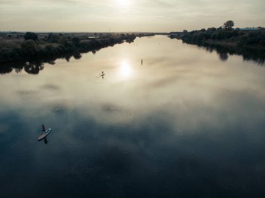 Göldeki SUP tahtalı turistlerin en iyi görüntüsü. Sörf yapan insanlarla dolu güzel, berrak bir su. Arka planda kürek çeken insanların olduğu deniz manzarası