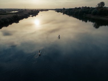 Göldeki SUP tahtalı turistlerin en iyi görüntüsü. Sörf yapan insanlarla dolu güzel, berrak bir su. Arka planda kürek çeken insanların olduğu deniz manzarası