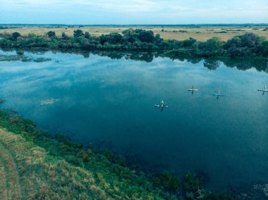 Göldeki SUP tahtalı turistlerin en iyi görüntüsü. Sörf yapan insanlarla dolu güzel, berrak bir su. Arka planda kürek çeken insanların olduğu deniz manzarası