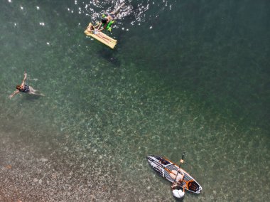 Stand Up Paddle tahtasında çekici bir kadın yemek masasında kürek çeken ve şeffaf suyun tadını çıkaran bir kadın. Tropik seyahat, seyahat tutkusu ve su aktivitesi konsepti. Gün batımı ve rahatlama