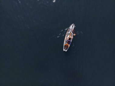 Stand Up Paddle tahtasında çekici bir kadın yemek masasında kürek çeken ve şeffaf suyun tadını çıkaran bir kadın. Tropik seyahat, seyahat tutkusu ve su aktivitesi konsepti. Gün batımı ve rahatlama