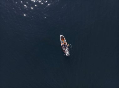 Stand Up Paddle tahtasında çekici bir kadın yemek masasında kürek çeken ve şeffaf suyun tadını çıkaran bir kadın. Tropik seyahat, seyahat tutkusu ve su aktivitesi konsepti. Gün batımı ve rahatlama
