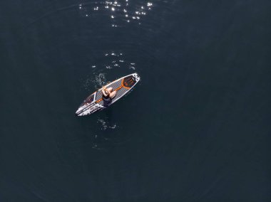 Stand Up Paddle tahtasında çekici bir kadın yemek masasında kürek çeken ve şeffaf suyun tadını çıkaran bir kadın. Tropik seyahat, seyahat tutkusu ve su aktivitesi konsepti. Gün batımı ve rahatlama